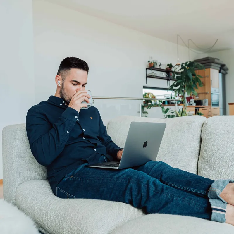 A man working on a laptop on a sofa
